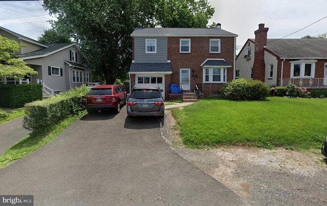 view of front of property featuring driveway, brick siding, and a front lawn