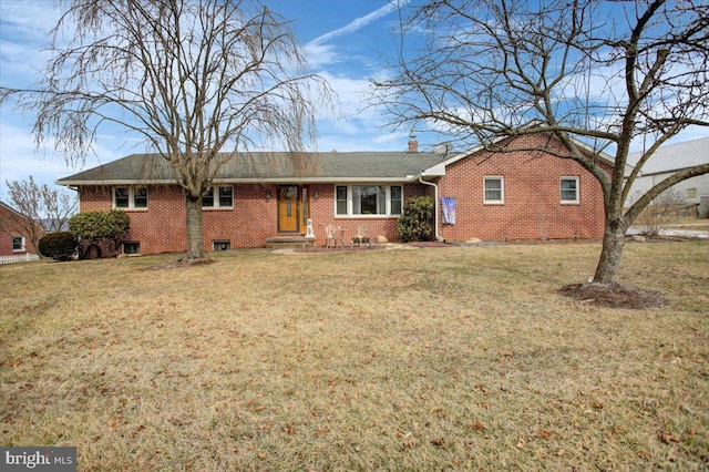 ranch-style home featuring brick siding, a chimney, and a front yard