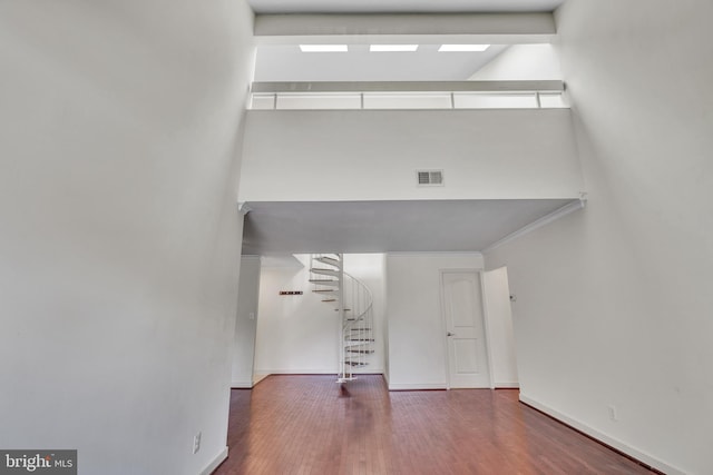 interior space with a towering ceiling, visible vents, wood finished floors, and stairs