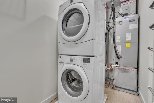 laundry room with laundry area, stacked washer and clothes dryer, and baseboards