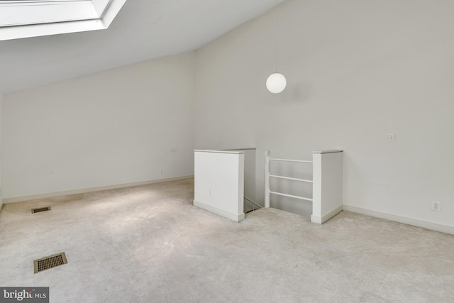 additional living space featuring visible vents, lofted ceiling with skylight, light colored carpet, and baseboards