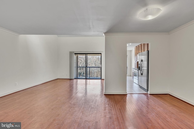 spare room with baseboards, light wood-style flooring, and ornamental molding