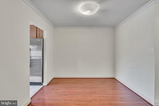 spare room featuring baseboards, light wood-style flooring, and crown molding