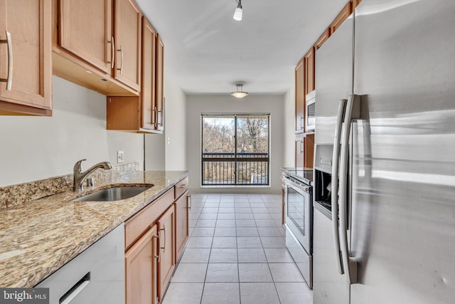 kitchen featuring light stone counters, stainless steel appliances, and a sink