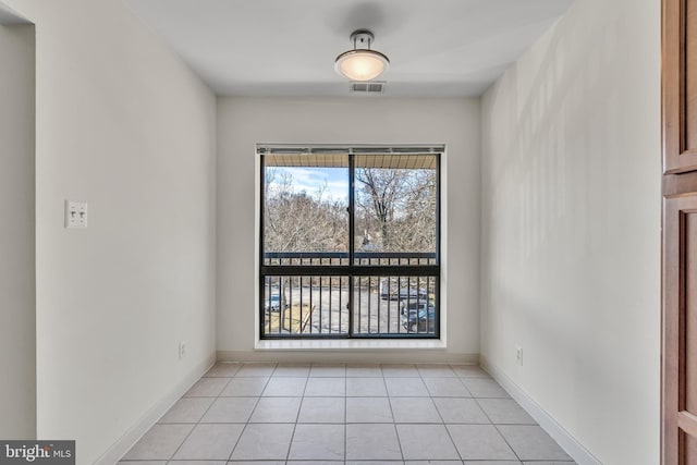 unfurnished room featuring light tile patterned floors, visible vents, and baseboards