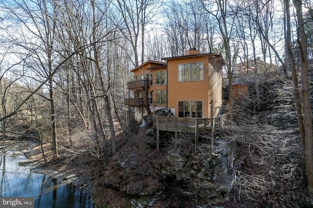 rear view of property with a chimney and a balcony