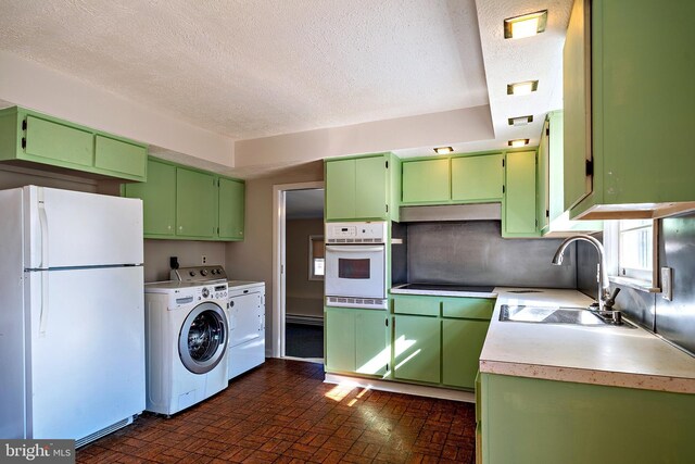 kitchen featuring white appliances, green cabinetry, a sink, light countertops, and washer and dryer