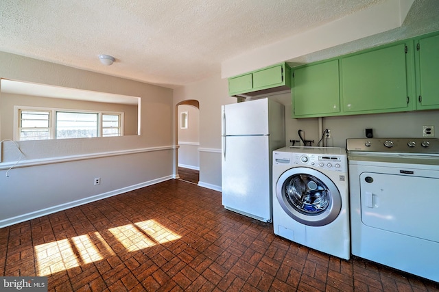 laundry area with cabinet space, arched walkways, brick floor, baseboards, and washing machine and clothes dryer