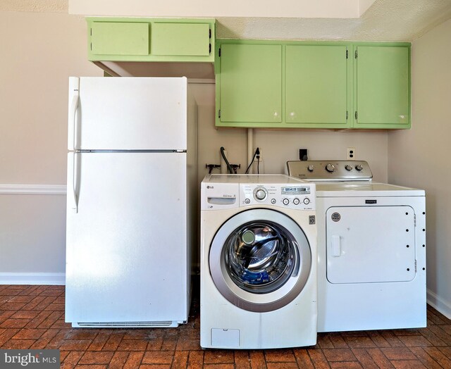 washroom with washer and clothes dryer, brick floor, and baseboards