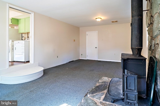 unfurnished living room featuring visible vents, washing machine and dryer, and a wood stove