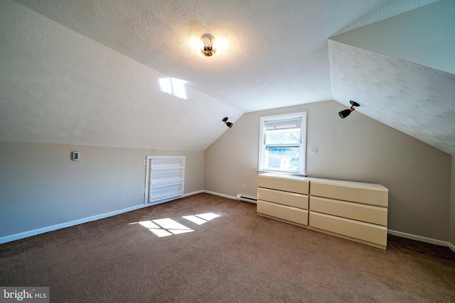 additional living space featuring vaulted ceiling, baseboards, baseboard heating, and a textured ceiling