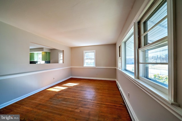 unfurnished room with baseboards and dark wood-style flooring