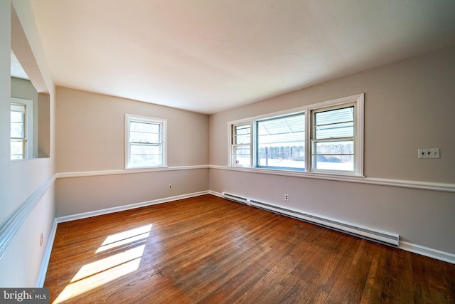 empty room with a wealth of natural light, baseboards, baseboard heating, and wood finished floors