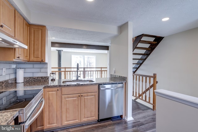 kitchen with dark wood-style floors, a sink, appliances with stainless steel finishes, a textured ceiling, and backsplash