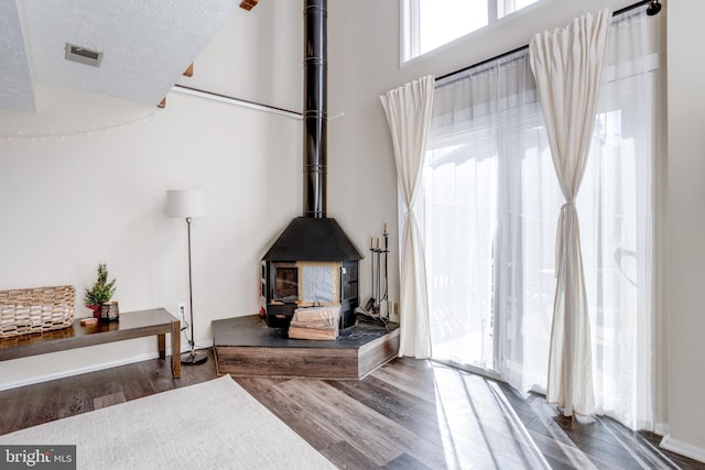 interior details with a textured ceiling, wood finished floors, and a wood stove