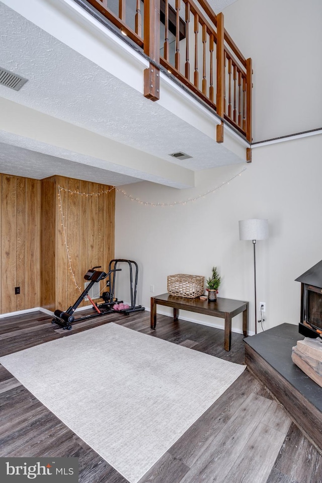 interior space with visible vents, wooden walls, wood finished floors, and a wood stove