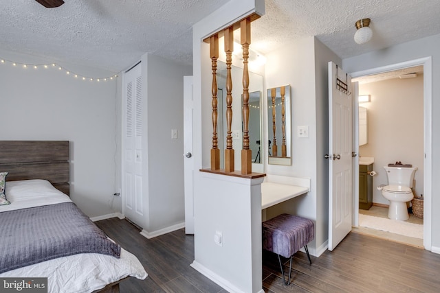 bedroom with wood finished floors, baseboards, ensuite bathroom, and a textured ceiling