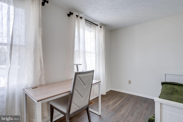 unfurnished office with a textured ceiling, dark wood-type flooring, and baseboards