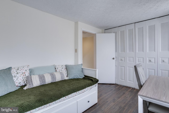 bedroom with a closet, a textured ceiling, and dark wood finished floors