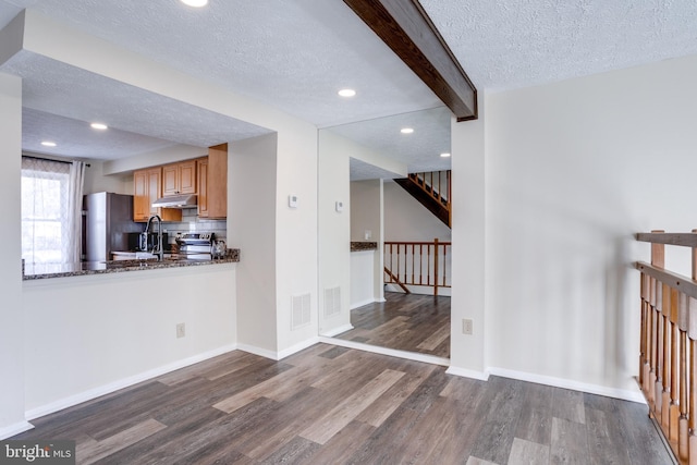 kitchen with visible vents, dark wood-type flooring, under cabinet range hood, freestanding refrigerator, and a textured ceiling