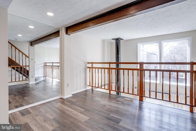 unfurnished room with baseboards, beam ceiling, recessed lighting, wood finished floors, and a textured ceiling