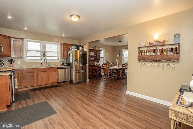 kitchen with hardwood / wood-style flooring, stainless steel appliances, a wealth of natural light, and decorative light fixtures