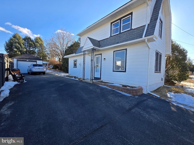 view of front of house with a garage and an outbuilding