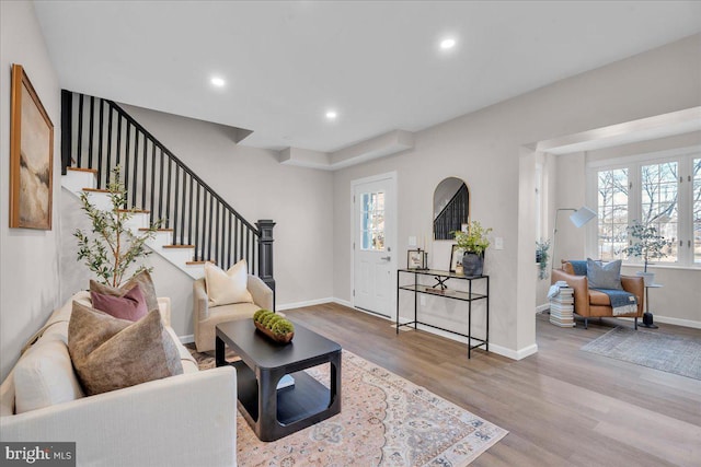 living room with recessed lighting, plenty of natural light, light wood finished floors, and stairs