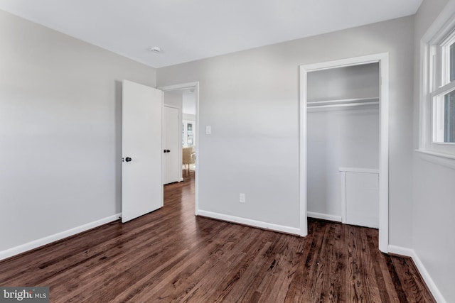 unfurnished bedroom featuring dark wood-type flooring and a closet