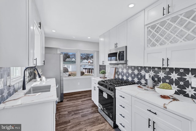 kitchen featuring white cabinetry, appliances with stainless steel finishes, sink, and light stone counters