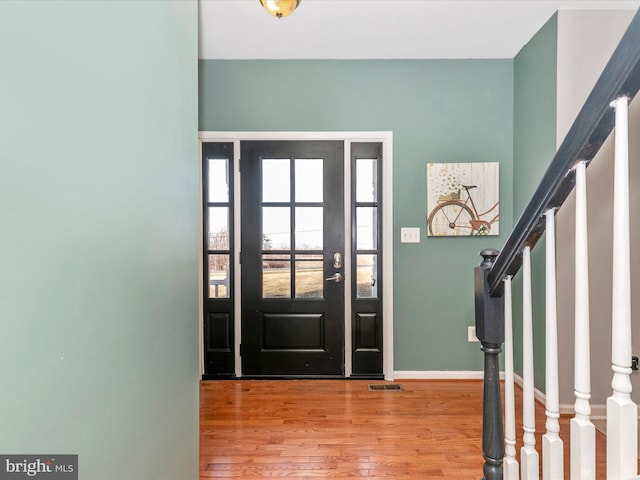 entryway featuring visible vents, stairway, baseboards, and wood finished floors