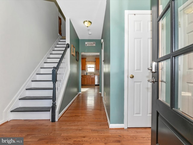 foyer entrance with stairs, wood finished floors, and baseboards