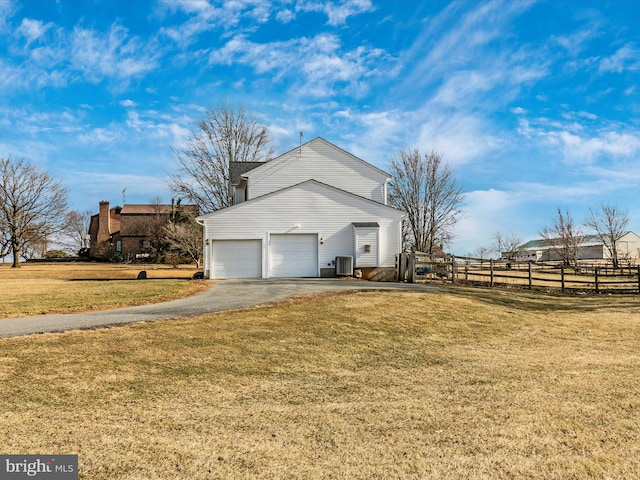 view of side of home featuring a lawn, central AC unit, fence, a garage, and driveway