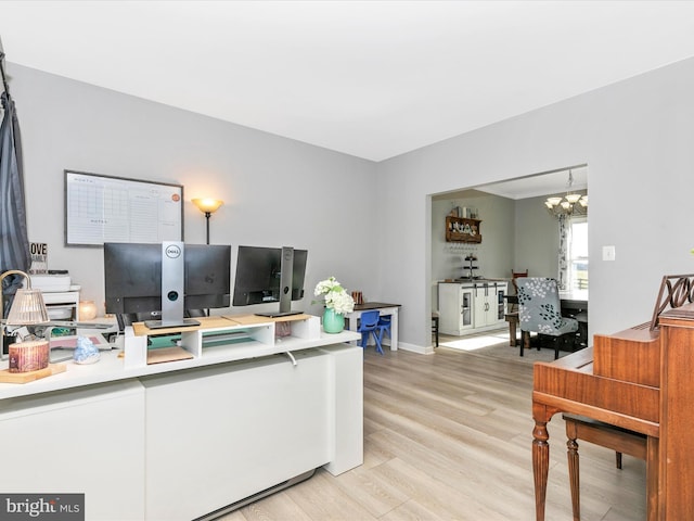 office featuring baseboards, light wood-type flooring, and a notable chandelier