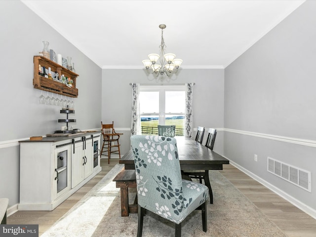 dining space with a chandelier, light wood-style flooring, visible vents, baseboards, and ornamental molding