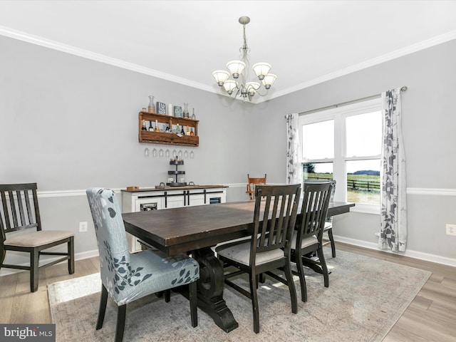 dining space with a notable chandelier, baseboards, light wood-style flooring, and crown molding