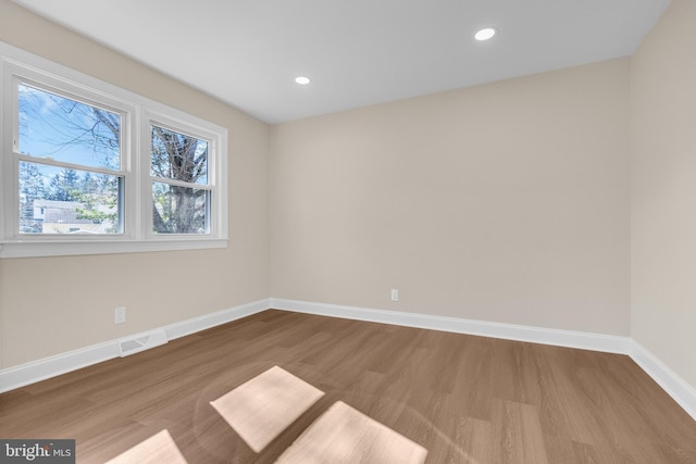 empty room with recessed lighting, visible vents, baseboards, and wood finished floors