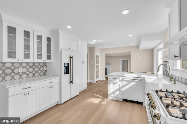 kitchen featuring white cabinetry, light countertops, decorative backsplash, high end appliances, and glass insert cabinets