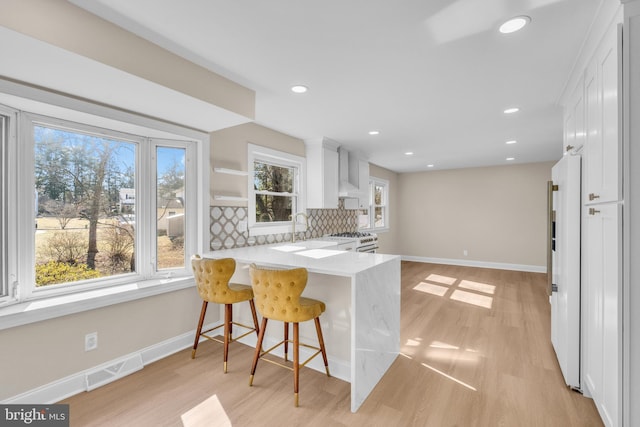 kitchen with light wood finished floors, visible vents, decorative backsplash, white cabinetry, and white range with gas stovetop