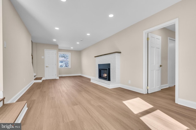 unfurnished living room with recessed lighting, a brick fireplace, baseboards, and wood finished floors