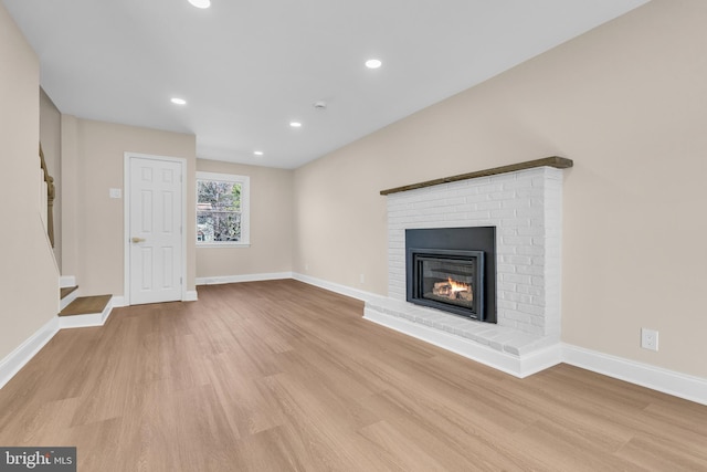 unfurnished living room featuring a fireplace, baseboards, and wood finished floors