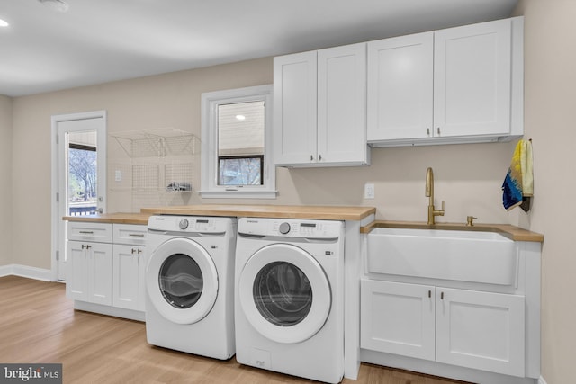 washroom with light wood-type flooring, cabinet space, a sink, and independent washer and dryer