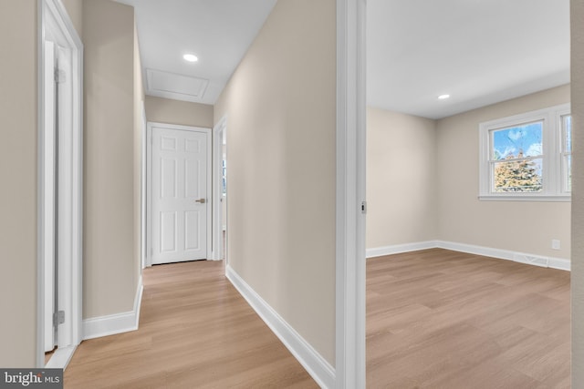 hallway with light wood-style floors, attic access, baseboards, and recessed lighting