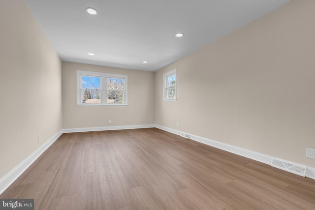 unfurnished room with recessed lighting, wood finished floors, visible vents, and baseboards