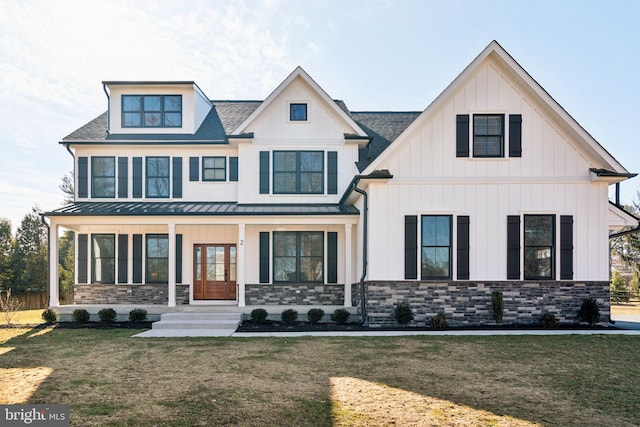 modern farmhouse style home featuring metal roof, a porch, a standing seam roof, and a front lawn