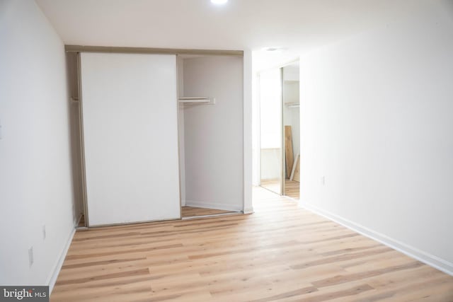 unfurnished bedroom with a closet, light wood-style flooring, and baseboards