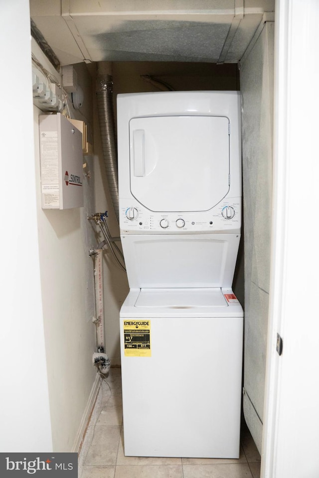 washroom with light tile patterned floors, laundry area, baseboards, and stacked washer / drying machine