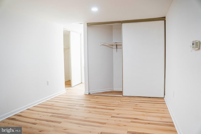 unfurnished bedroom featuring baseboards, light wood finished floors, a closet, and recessed lighting