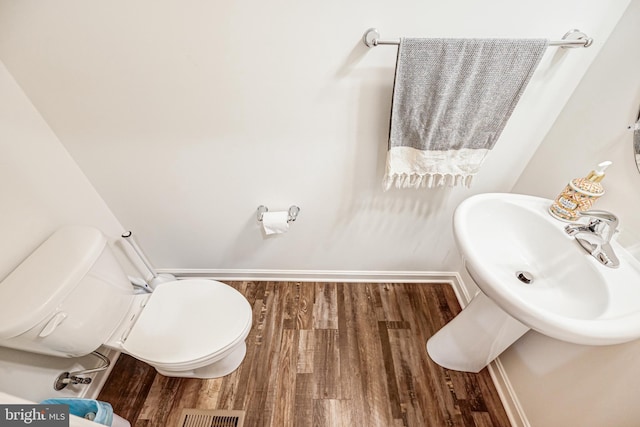 bathroom with toilet, baseboards, visible vents, and wood finished floors