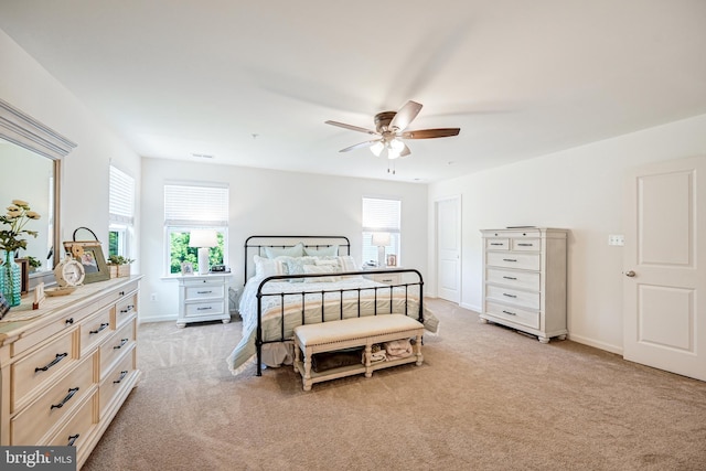 bedroom with baseboards, multiple windows, and light colored carpet